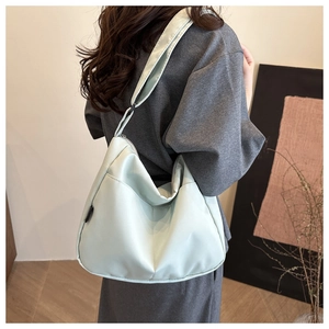 Detail of mint green nylon tote bag with smooth texture and side label on a shoulder