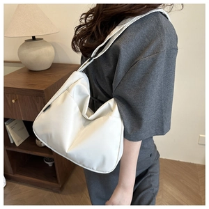 Detail of white half-moon crossbody bag with wide strap in a minimalist home setting