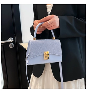 Close-up of a light blue French style handbag with textured panels and gold hardware