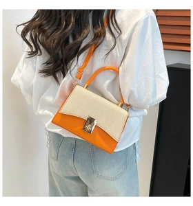 Détail du sac bandoulière bicolore en cuir orange, texture tissée et fermoir en métal doré