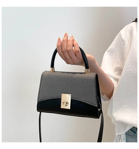Détail du sac à bandoulière avec rabat en tissu gris et poignée en métal doré
