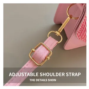 Detail of adjustable pink PU leather shoulder strap with gold metal buckle on a handbag