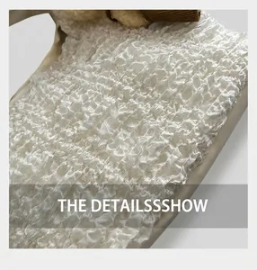 Close-up of white popcorn fabric with high-density 3D pleats and fleece trim details