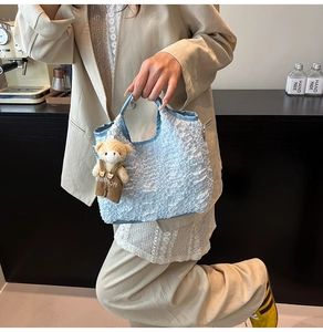 Detail of light blue bubble texture handbag featuring a cute teddy bear charm with fashion logo