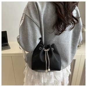 Détail du sac seau en velours côtelé noir avec chaîne argentée et perles blanches