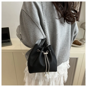 Detail einer schwarzen geflochtenen Beuteltasche mit Kette und Perlenzugverschluss