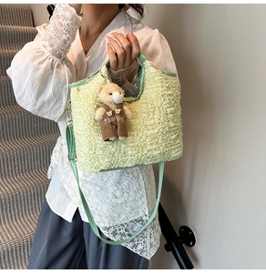 Detail of light green ruched handbag with a cute teddy bear pendant and fabric texture