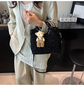 Detailed shot of black pleated tote bag with golden hardware and cute bear charm