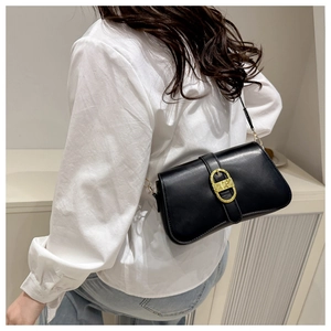 Fashionable black faux leather shoulder bag with a gold D-ring buckle on a female model