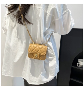 Detail of a ginger yellow quilted mini crossbody bag with a golden flower shaped lock clasp