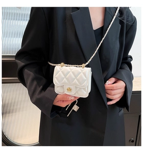 Close-up of a mini white quilted crossbody bag with a golden camellia flower clasp