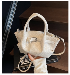 Dettaglio della borsa a mano bianca intrecciata con fibbia su scale di legno scuro