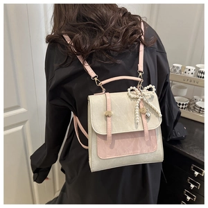 Détail du sac à dos bicolore avec pendentif nœud en perles et boucles en métal doré