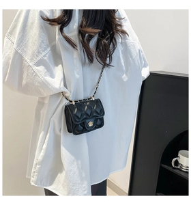 Detail of black quilted crossbody bag with gold camellia lock on a model back