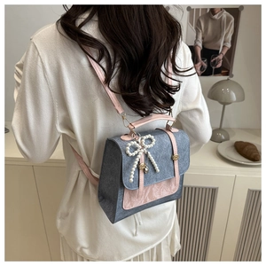 Détail du sac à dos en feutre gris avec garniture en cuir rose et breloque noeud perlé