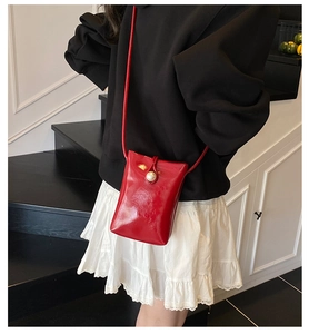 Mini red patent leather shoulder bag featuring a large pearl button on model