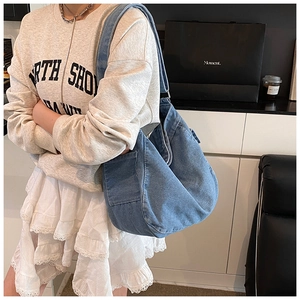 Side view of a large washed denim hobo bag featuring a functional side pocket design