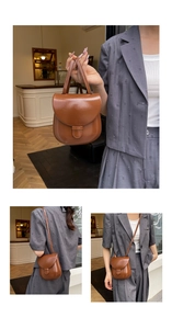 Detail of brown semi-circle flap bag with glossy finish and versatile carrying straps