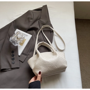 Dettaglio della borsa tote beige in pelle intrecciata con trama plissettata