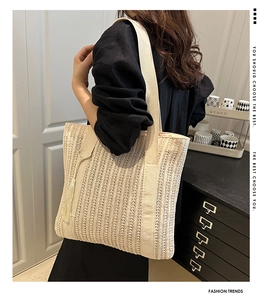 Detail of hand-woven beige tote bag with vertical stripes and stylish tassel charm