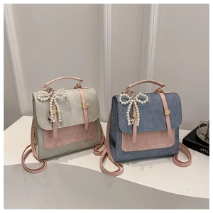 Detail of two-tone PU leather and denim mini backpacks with pearl bow pendants and gold buckles