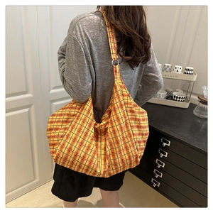 Detail of a large yellow plaid canvas tote bag with a soft crescent shape and wide strap