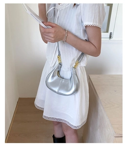 Detail of silver metallic hobo bag featuring smooth curves and elegant gold metal buckle