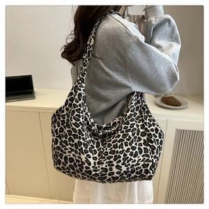 Detailed view of large leopard print canvas tote bag styled as a crossbody shoulder bag