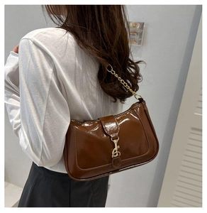 Détail d'un sac à bandoulière en cuir verni marron avec chaîne dorée et fermoir métal
