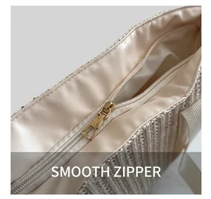 Detail of the smooth golden metal zipper closure on a beige woven tote straw bag