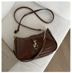 Vue détaillée du sac porté épaule marron foncé brillant avec chaîne dorée sur tissu