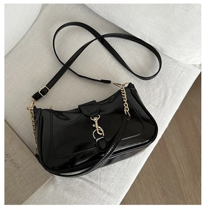Gros plan du sac en cuir verni noir avec fermoir métallique doré et détails de chaîne