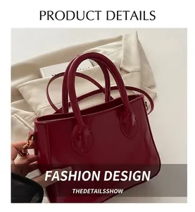 Detail view of red glossy leather handbag with crossbody strap and smooth stitching