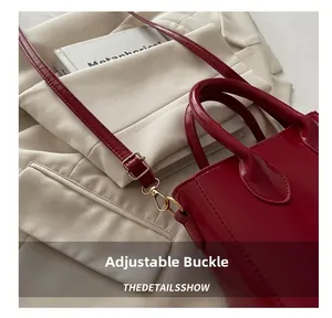 Detail of red patent leather handbag showing adjustable strap and gold metal buckles