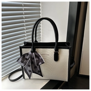 Close-up of white snakeskin pattern bag with black trim and elegant polka dot silk scarf