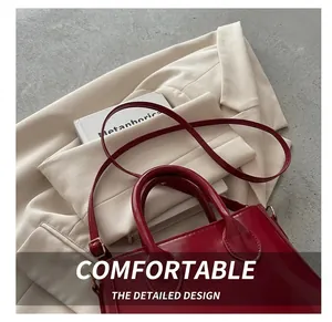 Detail view of red glossy patent leather handbag with golden hardware and round handle