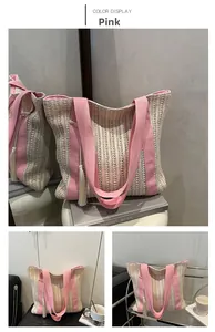 Detail of hand-woven straw tote bag with pink canvas straps and white cotton tassel