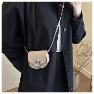 Détail d'un mini sac beige en cuir grainé avec un fermoir rotatif argenté en forme de cœur