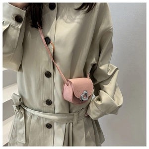 Mini sac à bandoulière rose en cuir grainé avec fermoir cœur sur un trench-coat