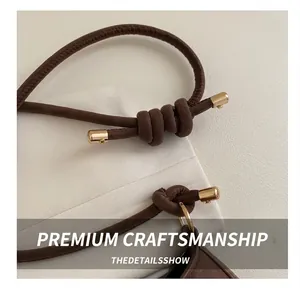 Detail of soft dark brown leather strap with elegant knot and gold metal hardware finish
