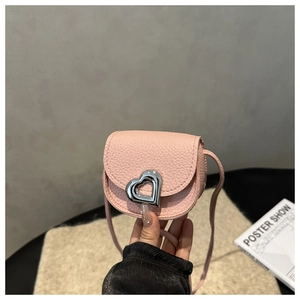 Close-up of pink litchi grain leather saddle bag with silver heart-shaped lock detail