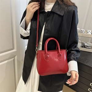 Glossy red patent leather handbag for women featuring top handles and adjustable shoulder strap