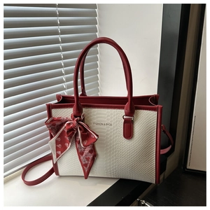 Detail view of white crocodile pattern tote bag with red leather trim and silk scarf