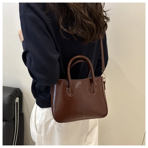 Close-up of deep brown glossy tote bag showing textured finish and sleek shoulder strap