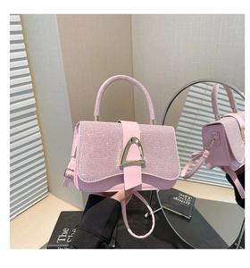 Close-up of pink rhinestone handbag with gold triangle clasp and top handle detail