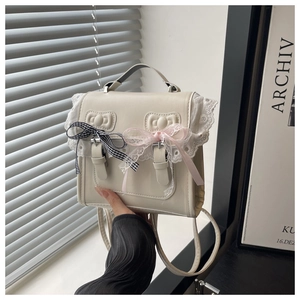 Close-up of cream lace handbag with elegant checkered and pink bow details