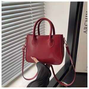 Detail of red synthetic leather mini tote bag with adjustable strap and gold metal buckle
