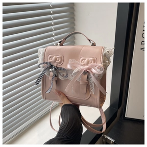 Detail of pink PU backpack with white lace edges and decorative black plaid bows