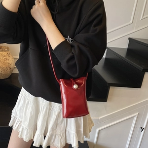 Glossy red mini crossbody bag with pearl buckle decoration on a female model