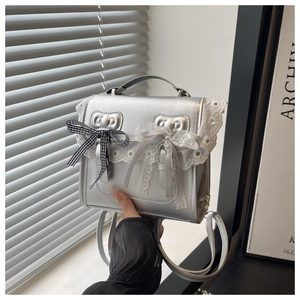 Detail of silver dual-use backpack with lace edges and bow accents on flap